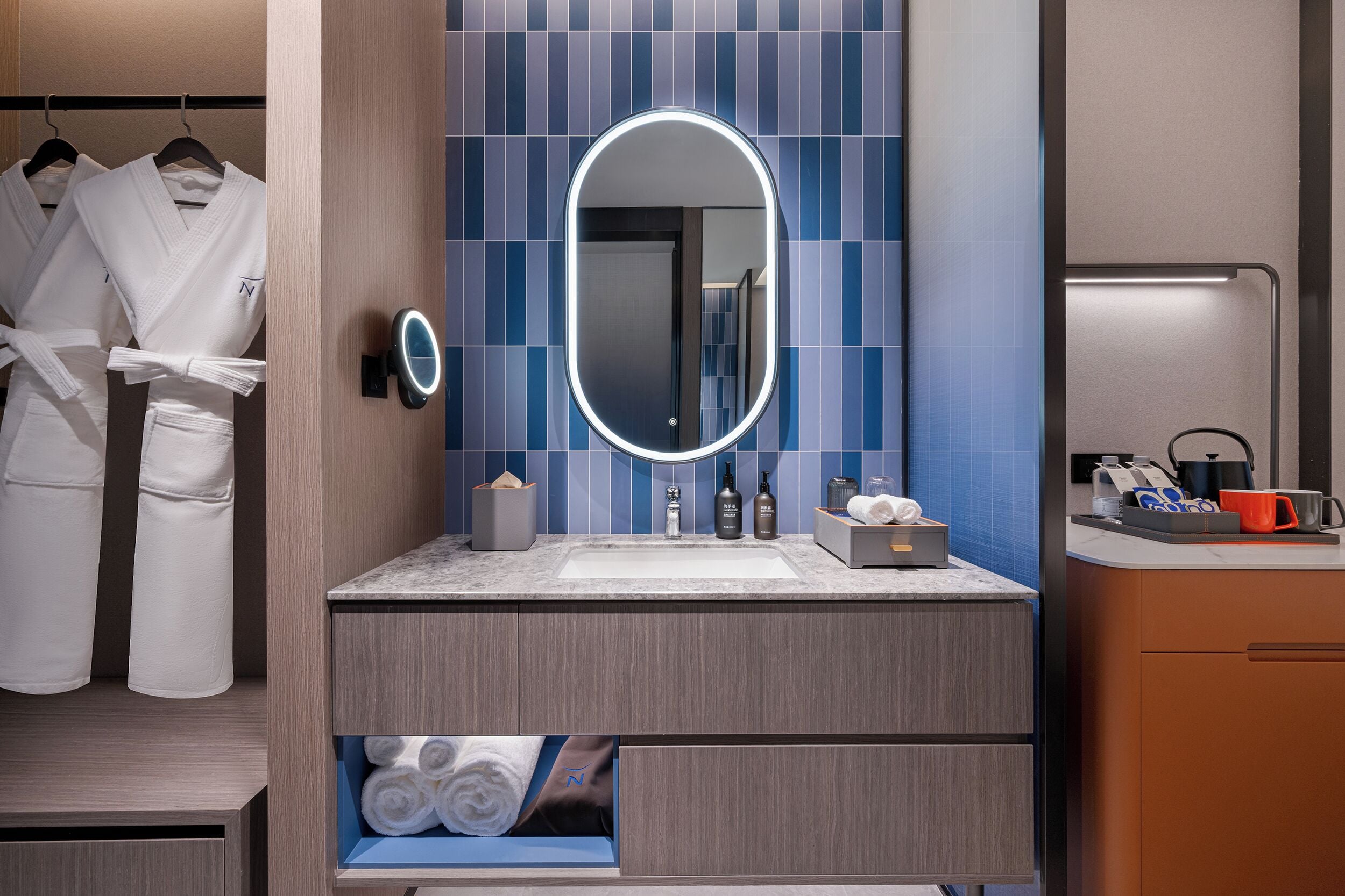 Un baño moderno con tocador, espejo con luces, toallero y retrete.