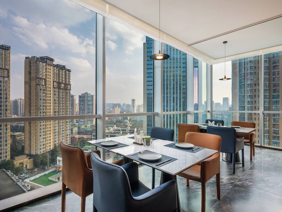 Comedor con vista a la ciudad, muebles modernos y ventanas amplias.