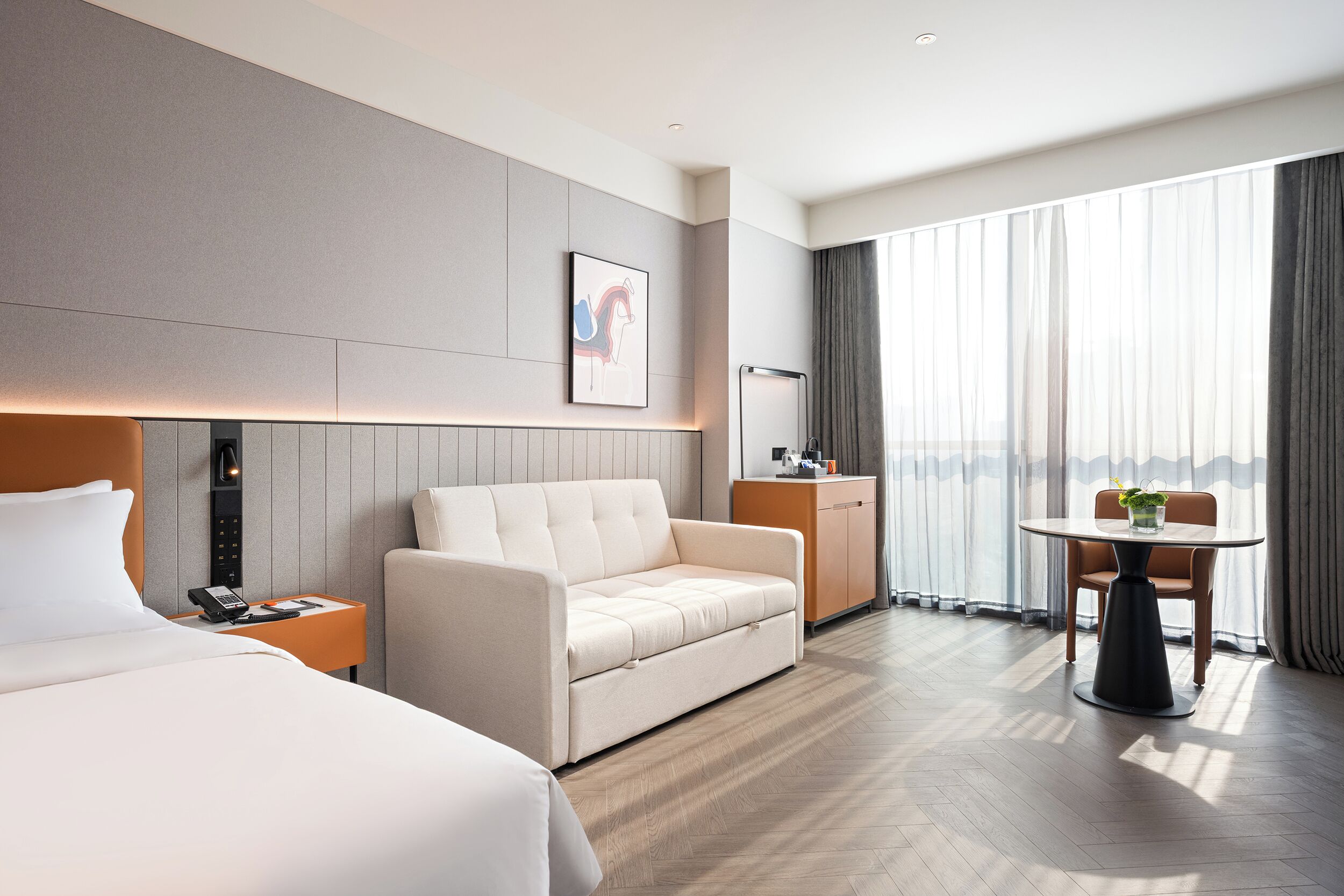 A hotel room with a bed, a sofa, a desk, and a dining table.