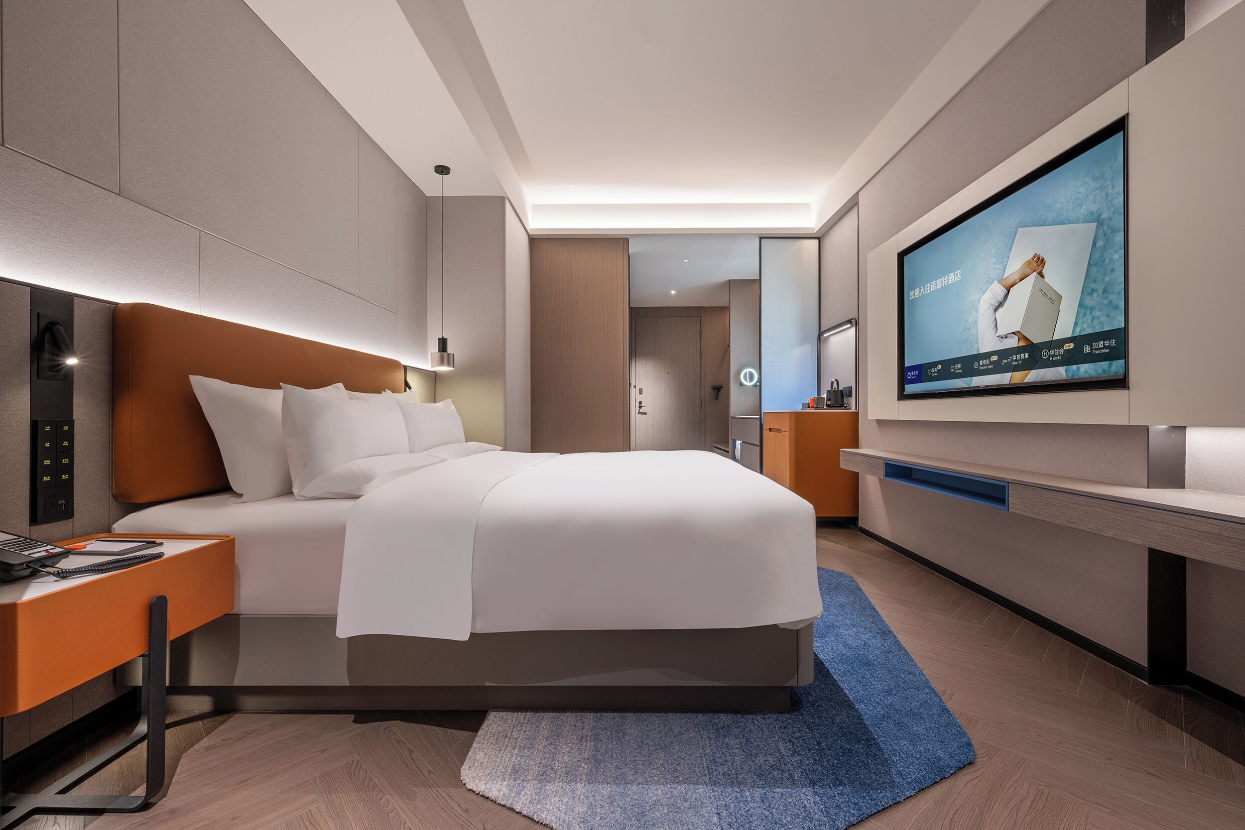 A modern hotel room with a large bed, a desk, a television, and a bathroom visible through an open door.
