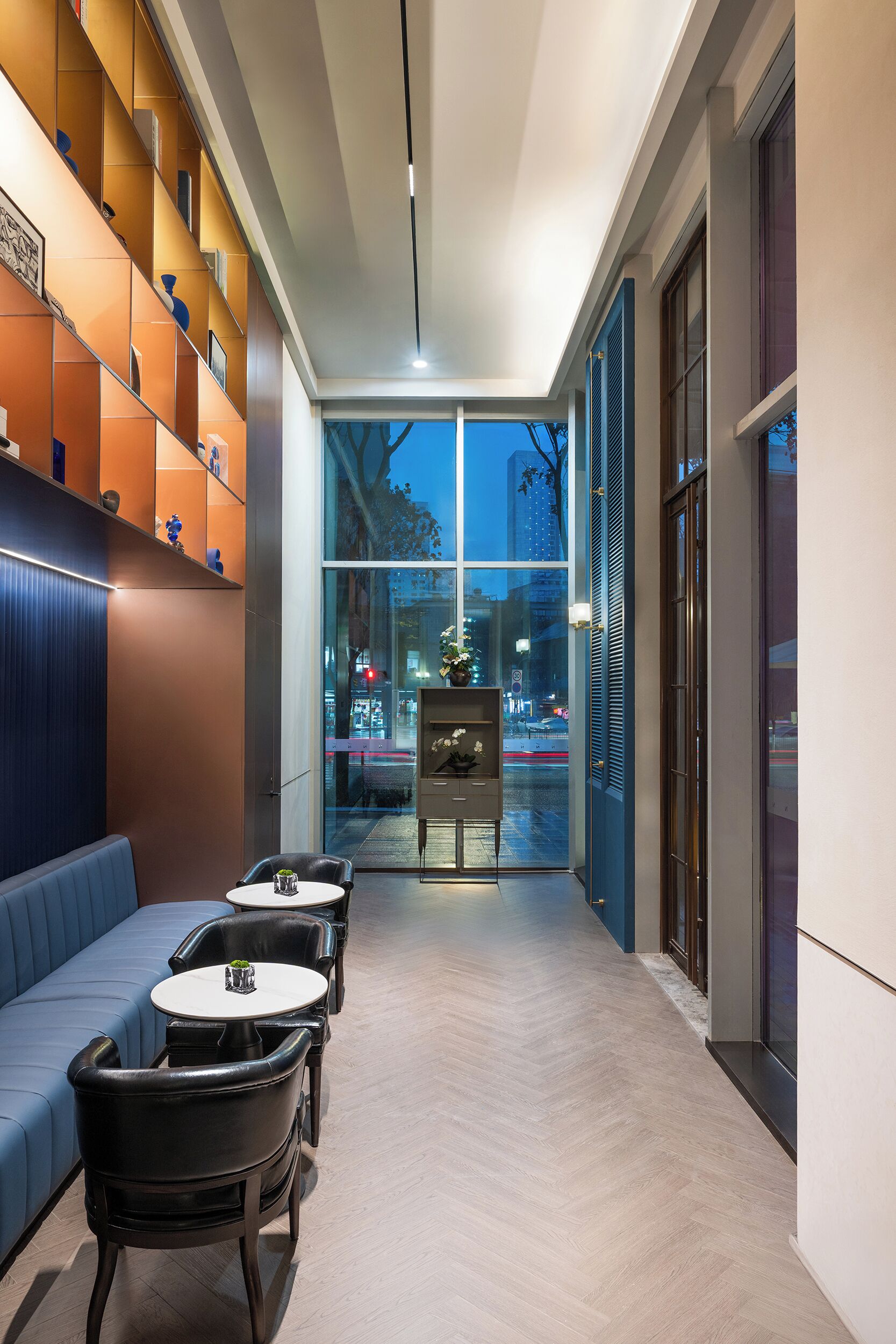 A modern interior with a seating area, a staircase, and a view of the city.