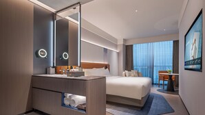 A modern hotel room with a large bed, a vanity with a mirror, and a view of the city. - Novotel Chengdu Chunxi Road (Chengdu)