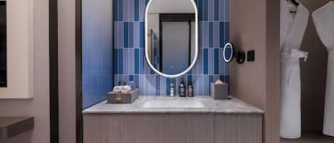 A modern bathroom with a large mirror, a sink, and a towel rack.