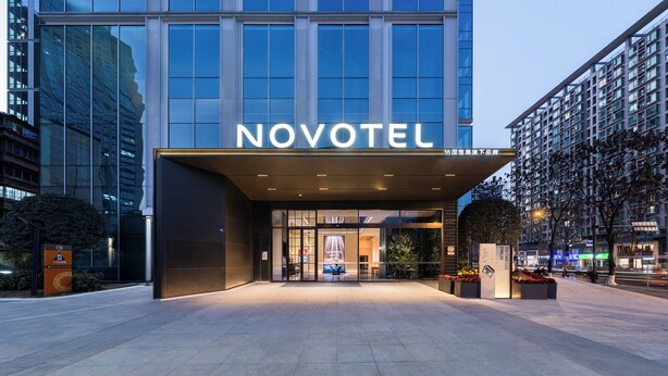 A modern hotel entrance with a large glass facade, a prominent 'NOVOTEL' sign, and a well-lit entrance area. - Novotel Chengdu Chunxi Road (Chengdu)