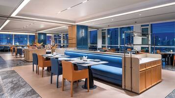 A modern restaurant with a blue booth seating area, wooden cabinets, and a city view.