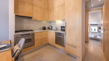 Eine kompakte Küche mit Holzschränken, Edelstahlgeräten und einem Essbereich mit Stuhl und Tisch.