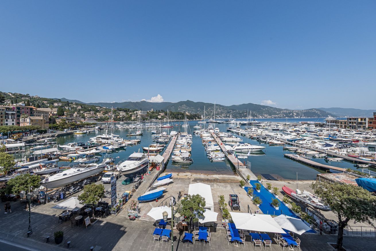 Un port de plaisance où sont amarrés de nombreux bateaux, un ciel dégagé et un paysage vallonné en arrière-plan.