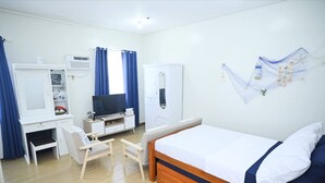 A hotel room with a bed, a desk, a chair, a television, and a wardrobe. - Condotel in SM Trece Martires (Trece Martires)