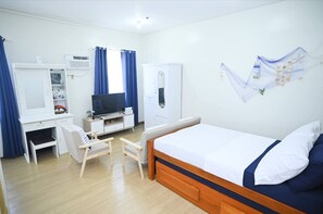 A hotel room with a bed, a desk, a chair, a television, and a wardrobe. - Condotel in SM Trece Martires (Trece Martires)