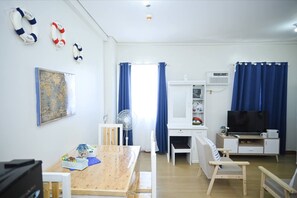 A room with a wooden table, chairs, a desk, a television, and a map on the wall. - Condotel in SM Trece Martires (Trece Martires)