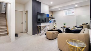 Ein modernes Wohnzimmer mit Flachbildfernseher, einer Couch, einem Couchtisch und einem Essbereich mit einer Mikrowelle.