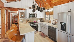 Una cocina con armarios blancos, estufa, microondas y refrigerador.