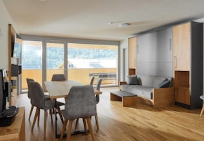 A modern living room with a dining area, a sofa, and built-in cabinets.