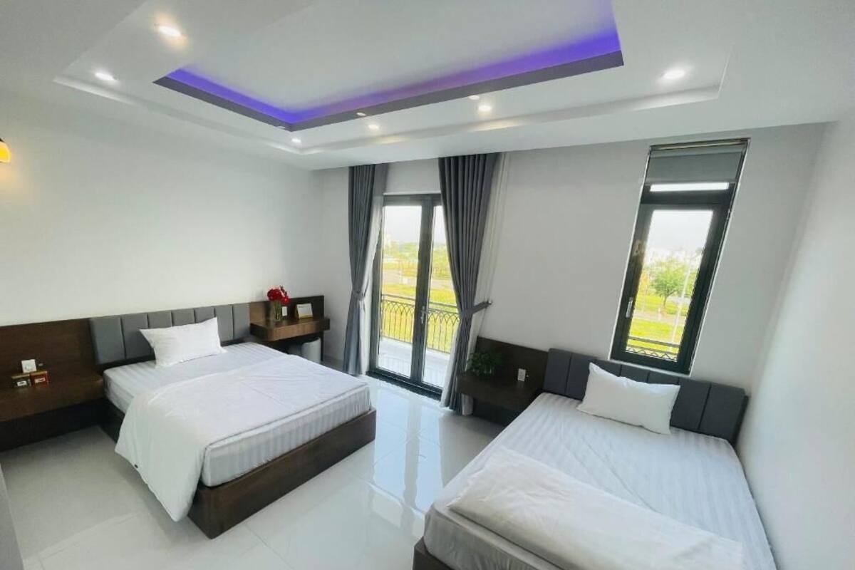 Habitación de hotel con dos camas, balcón y diseño moderno.