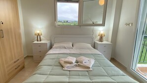 A bedroom with a bed, bedside lamps, a window, and an air conditioning unit. - Apartment 'Olyvia' with Sea View, Wi-Fi and Air Conditioning (Plaka Litochorou)