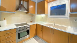 A modern kitchen with wooden cabinets, a stainless steel oven, a sink, and a window with a view. - Apartment 'Olyvia' with Sea View, Wi-Fi and Air Conditioning (Plaka Litochorou)