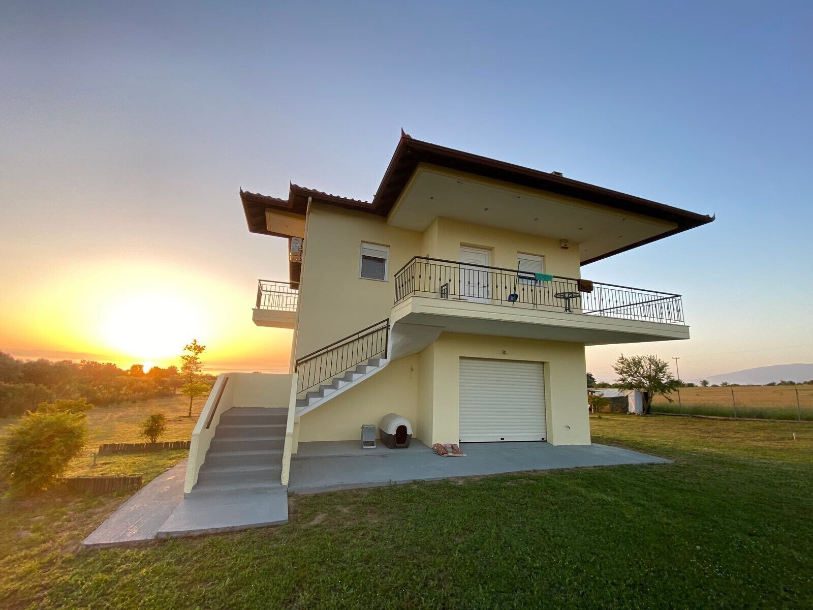 Ein zweistöckiges Haus mit Balkon, Garage und einer Treppe, die zu der oberen Etage führt.