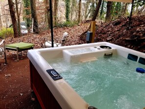 A hot tub in a forested area with a chair and a bench nearby. - Gold Miners Cabin - Mountain Retreat for the Whole Family - Sleeps 9 (Helen)