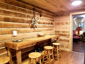 A wooden interior with a bar area, stools, and a hanging decoration. - Gold Miners Cabin - Mountain Retreat for the Whole Family - Sleeps 9 (Helen)