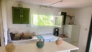 A compact kitchen with a sink, stove, refrigerator, and a window providing natural light. - GITE DU MARAIS DE SUZANNE (Suzanne)