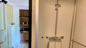 A walk-in shower with a handheld showerhead, a wall-mounted faucet, and a drain. - GITE DU MARAIS DE SUZANNE (Suzanne)