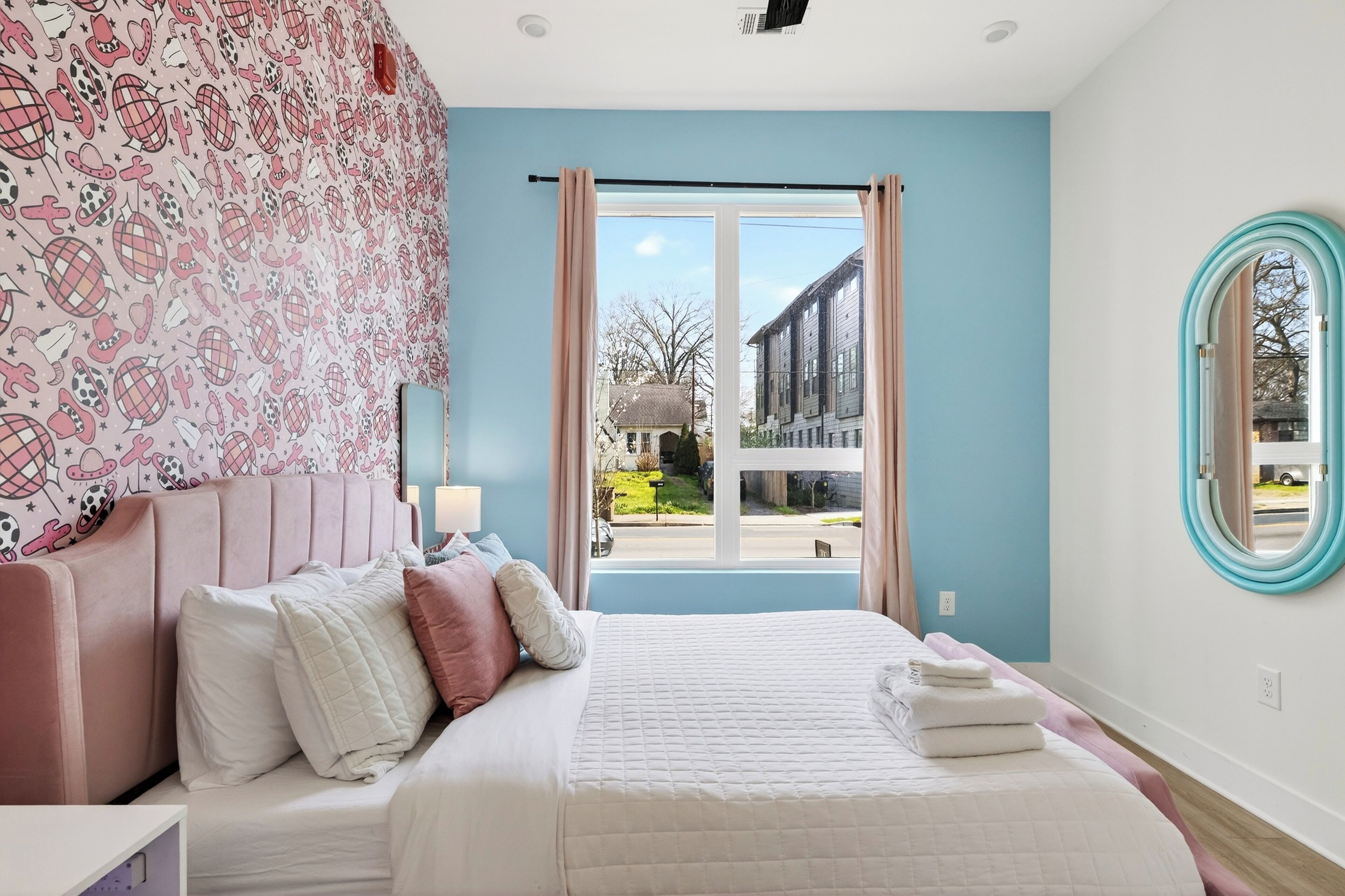 Un dormitorio con cama, almohadas, una ventana y vistas al exterior.