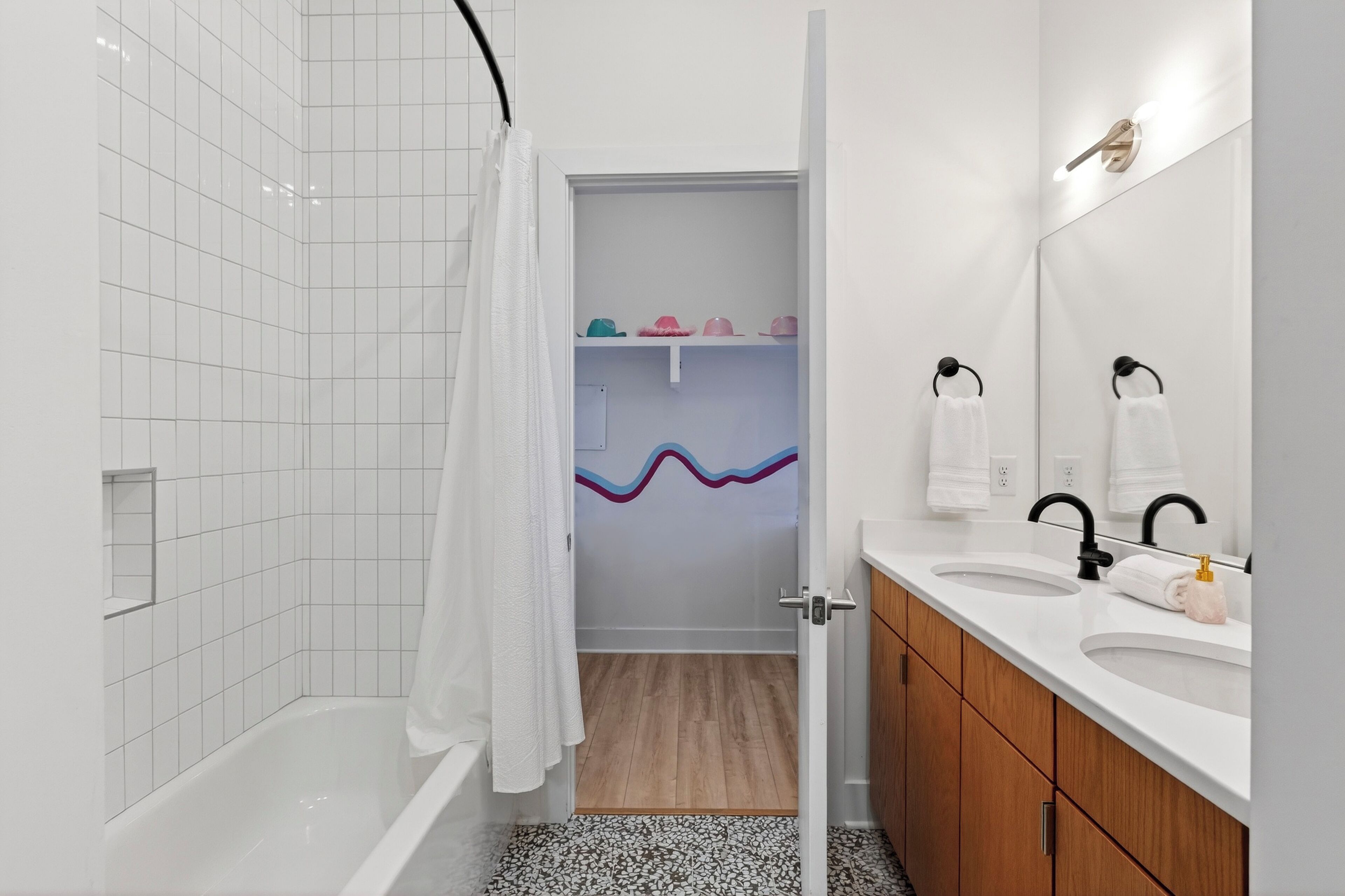 Un baño con bañera, dos lavamanos, un espejo y cortina de ducha.