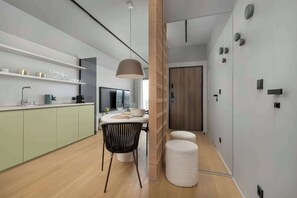 A modern kitchen with a dining area, a pendant light, and a wooden door. - Stylish Apartment | Parking, Gym and Cinema in the Building (Katowice)