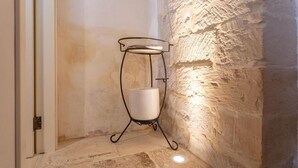 A corner with a white door, a textured stone wall, and a metal floor lamp. - Masseria Torre Sant'Andrea  (Borgagne)