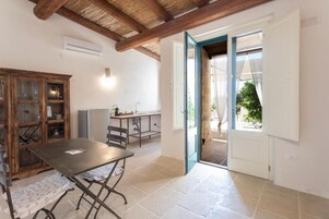 Una habitación con una mesa, sillas, un armario y una puerta que da al exterior.