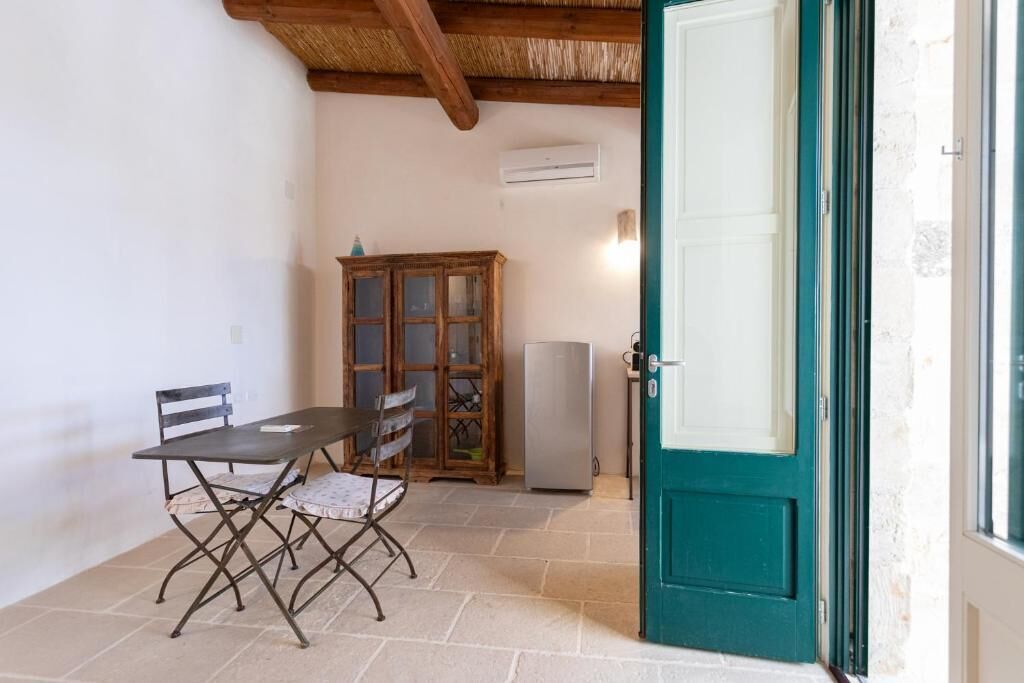 Um quarto com uma mesa, cadeiras, um armário, uma porta e um aparelho de ar condicionado.