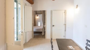 A room with a bed, a table, and a bench. There are doors leading to other rooms. - Masseria Torre Sant'Andrea  (Borgagne)