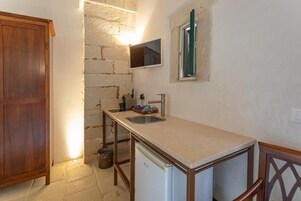 Una cocina compacta con un lavamanos, un refrigerador pequeño y un armario de madera.