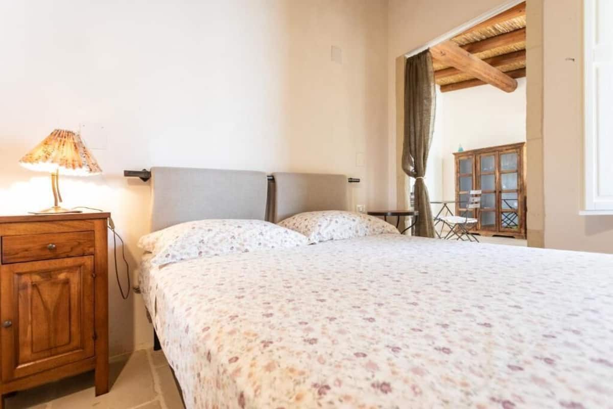 A bedroom with a bed, a nightstand, a lamp, and a wooden cabinet.