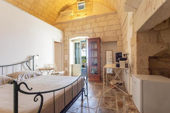 A bedroom with a bed, a desk, a cabinet, and a small table. - Masseria Torre Sant'Andrea (Borgagne)