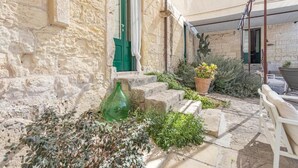 A stone building with a green door, outdoor seating, and potted plants. - Masseria Torre Sant'Andrea  (Borgagne)