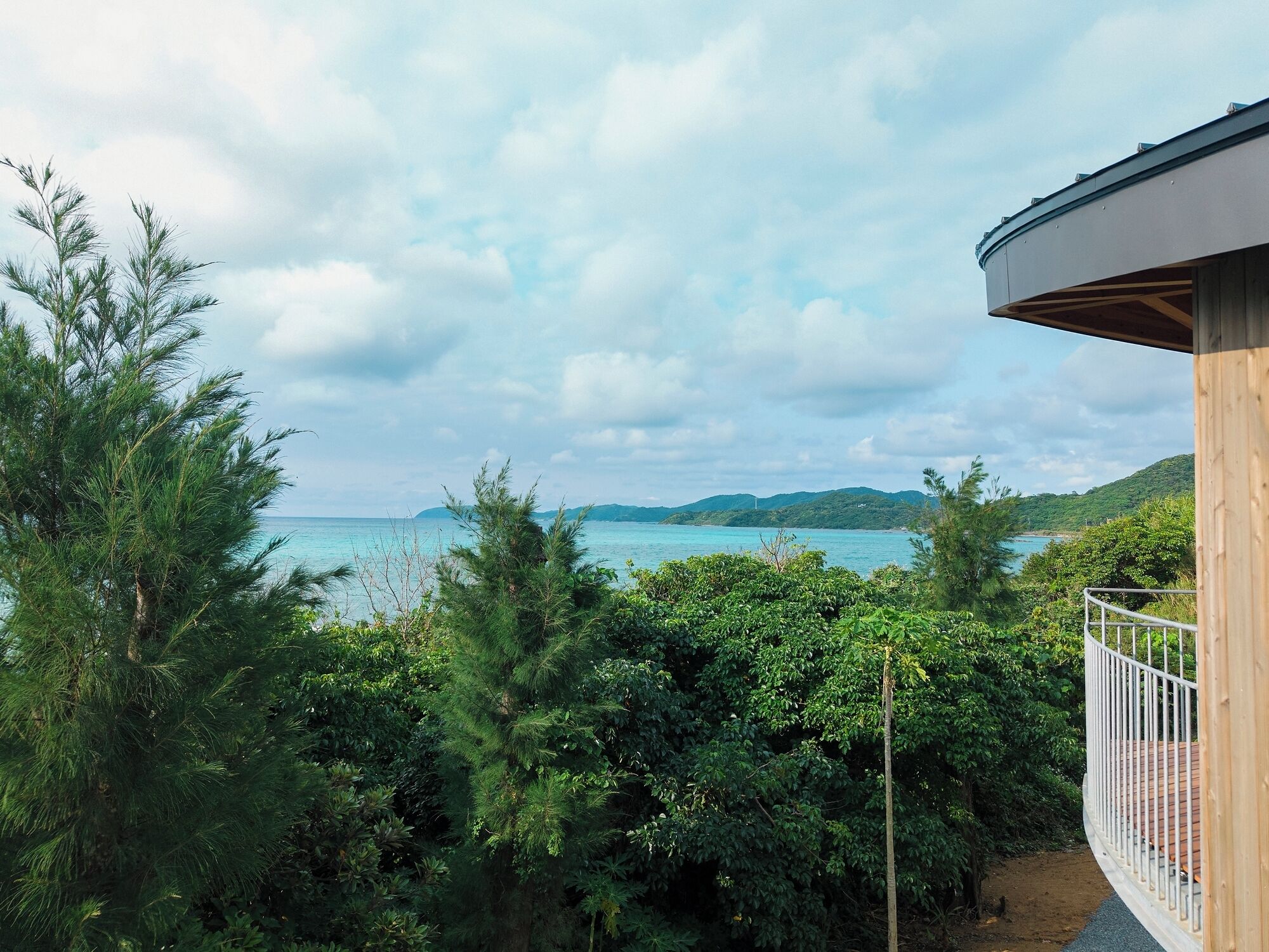 A balcony with a view of the sea and mountains.