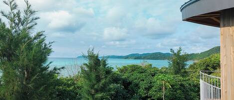A balcony with a view of the sea and mountains.