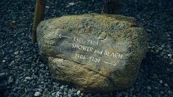 Een rots met richting pijlen en tekst die paden aangeeft naar 'SHOWER en BEACH' en '2401-2404'.