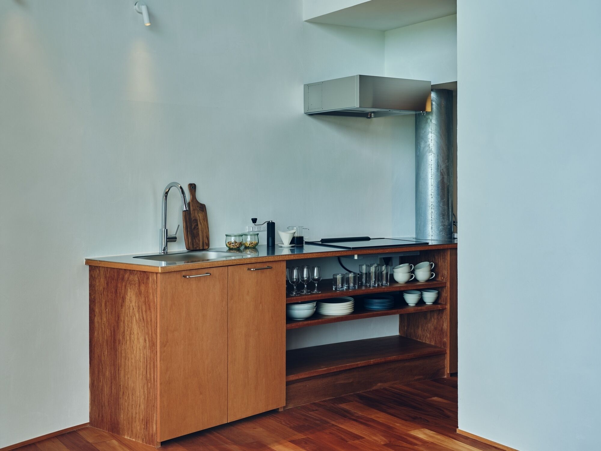 A compact kitchen with wooden cabinets, a stainless steel sink, and a range hood.