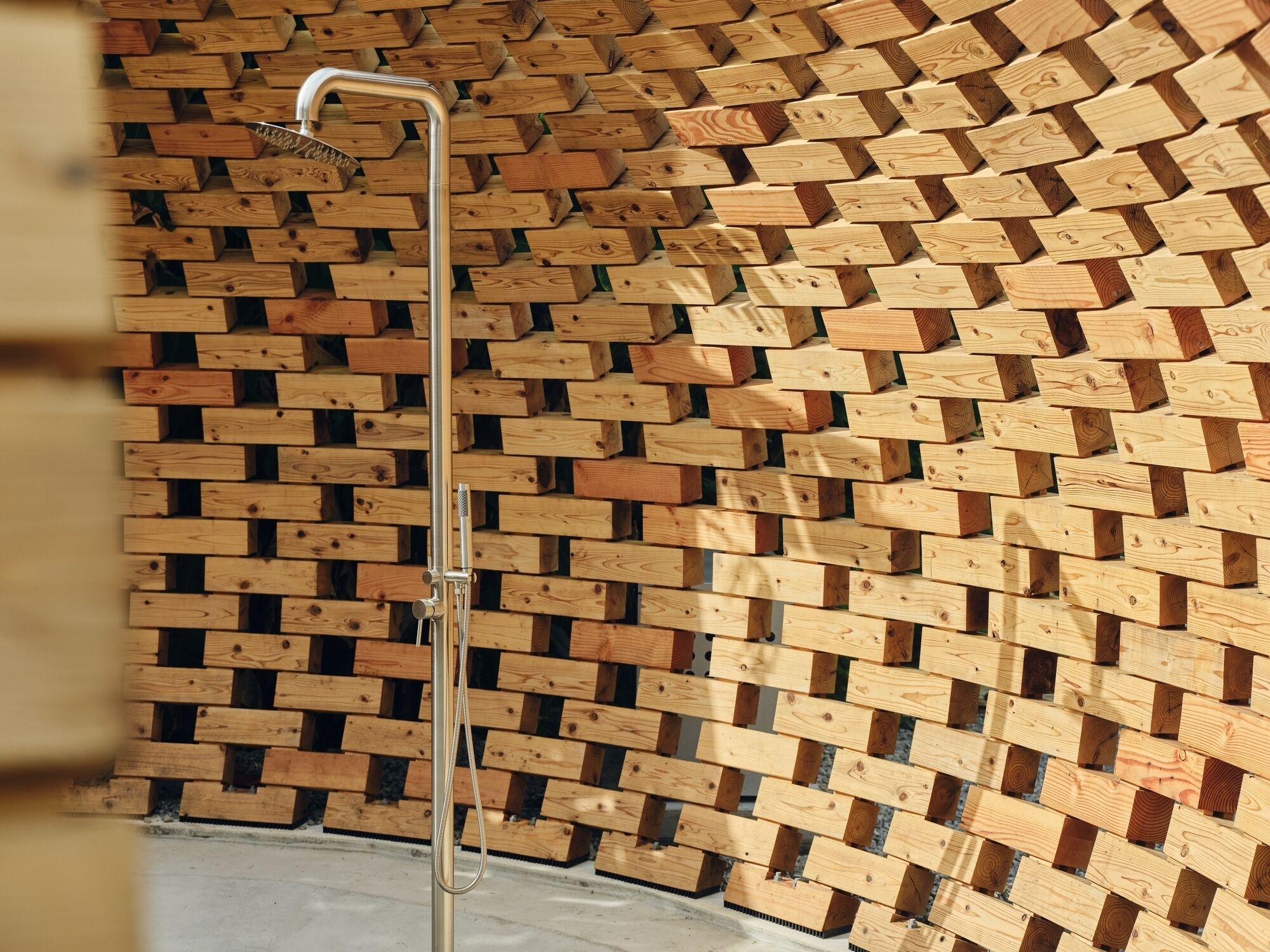A shower with a wooden wall backdrop.
