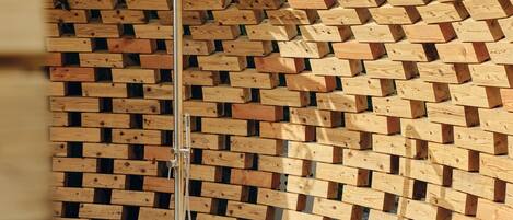 A shower with a wooden wall backdrop.