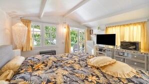 A bedroom with a bed, TV, dresser, and a view of greenery outside. - Guesthouse 'Casa Caro' with Mountain Views, Wi-Fi, and Air Conditioning (Estepona)