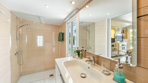 A modern bathroom with a shower, sink, and large mirror. - Guesthouse 'Casa Caro' with Mountain Views, Wi-Fi, and Air Conditioning (Estepona)
