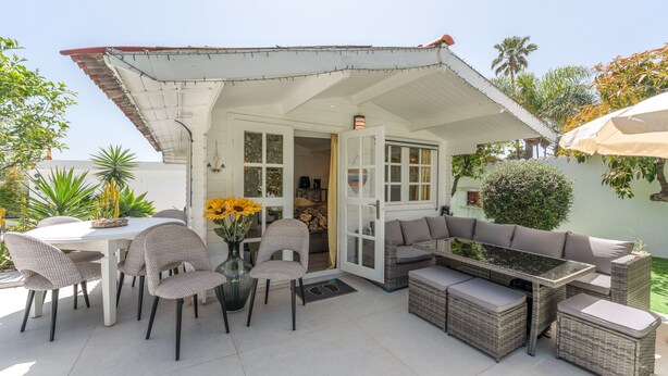 A patio area with a dining table, chairs, a sofa, and a small table with a lamp. - Guesthouse 'Casa Caro' with Mountain Views, Wi-Fi, and Air Conditioning (Estepona)