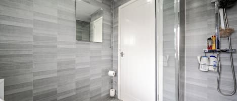 A modern bathroom with a toilet, a shower, and a glass-enclosed shower area.