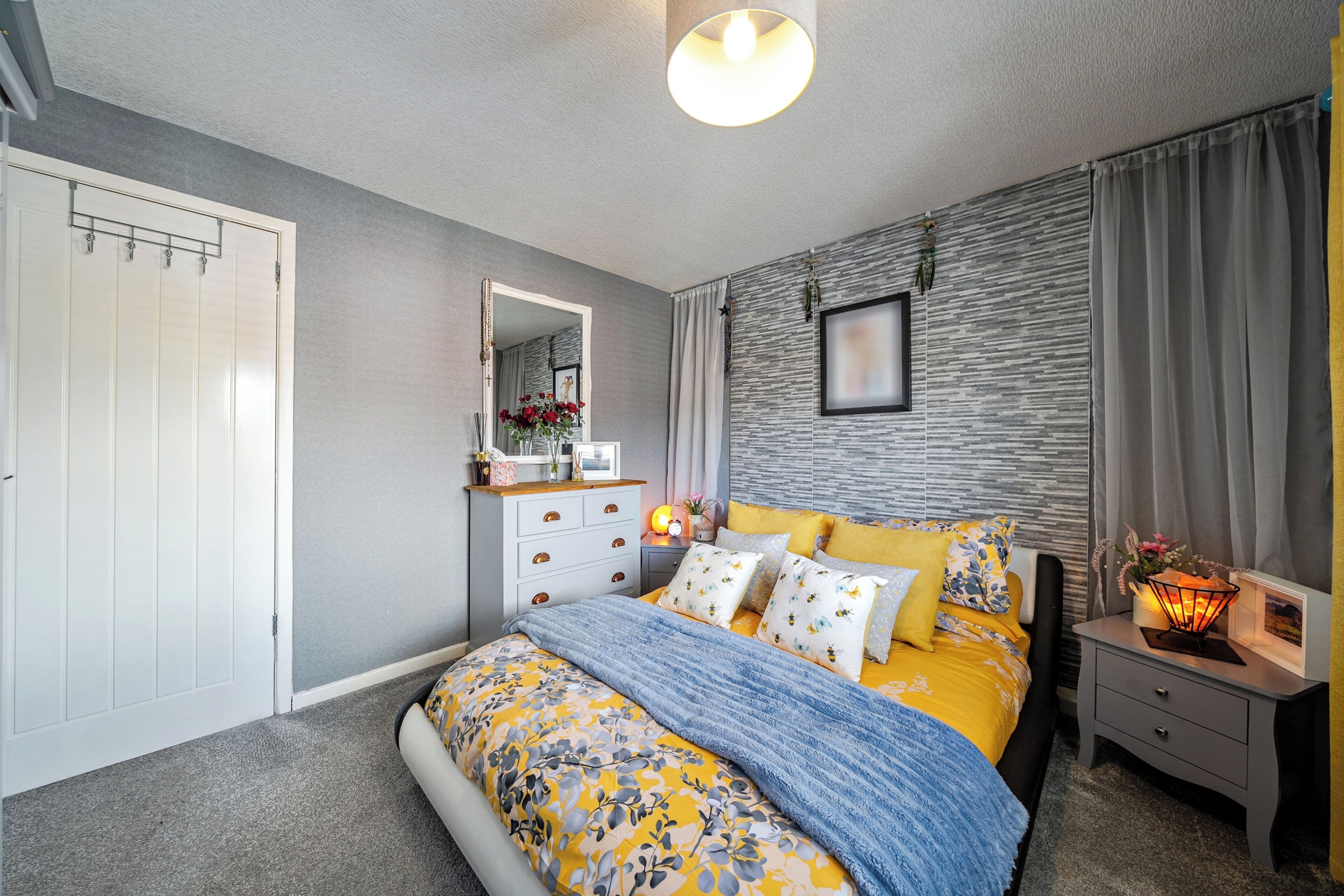 Une chambre à coucher comprenant un lit, une commode, une table de chevet et un miroir.