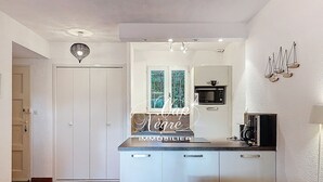 Een kleine keuken met een magnetron, een klein raam en een witte kast.
