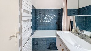 Een badkamer met een bad, een wastafel en een spiegel.