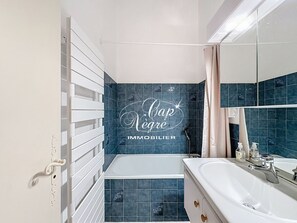 Une salle de bain avec une baignoire, un lavabo et un miroir.